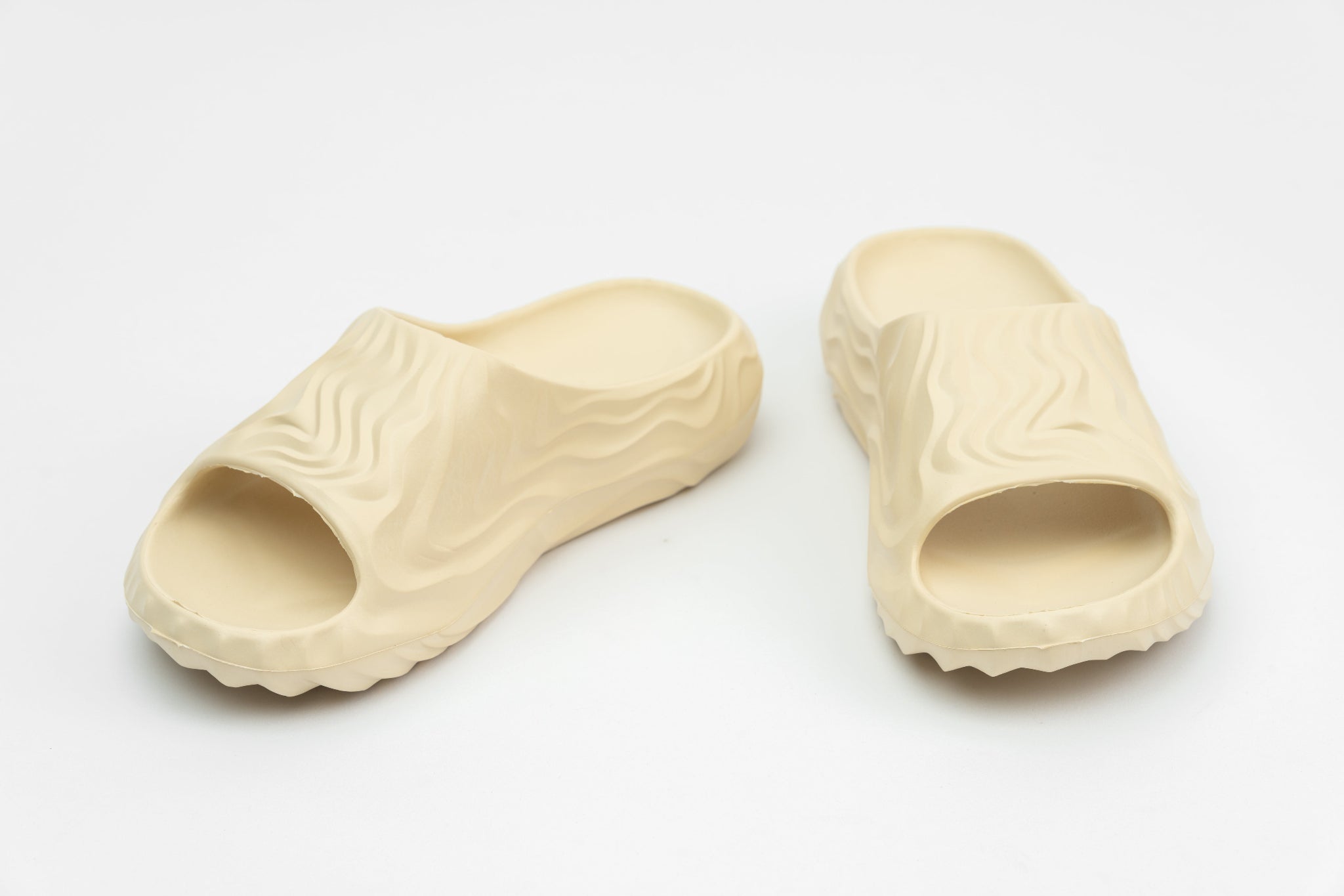 Pair of beige slippers with textured sole on a light gray background