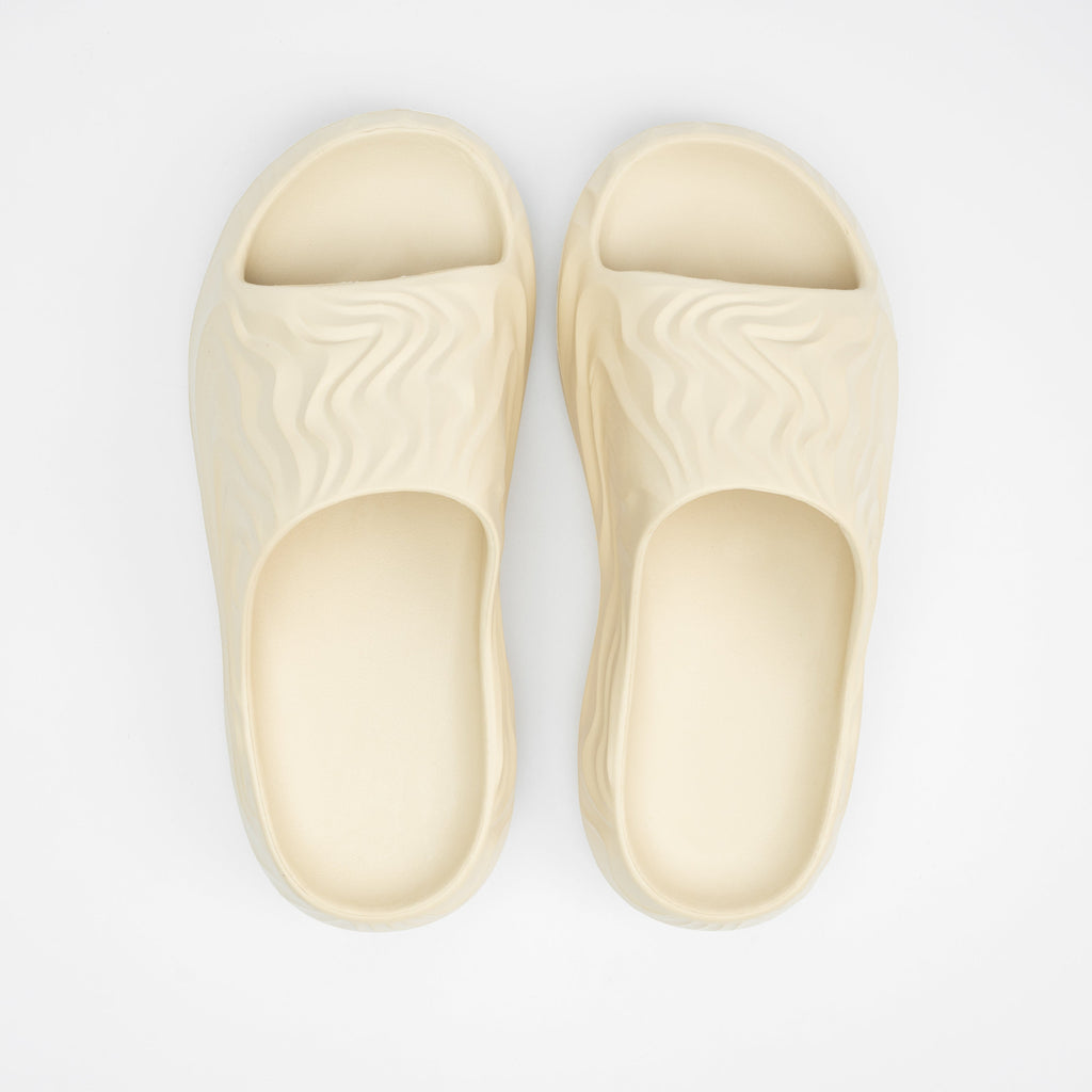 Pair of beige slippers on a light gray background